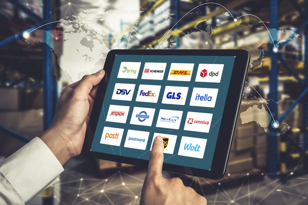 Henkilö käyttää tablettia, jonka näytöllä näkyy eri logistiikkayritysten logoja, kuten Posti, Matkahuolto, DHL, UPS ja Omniva.